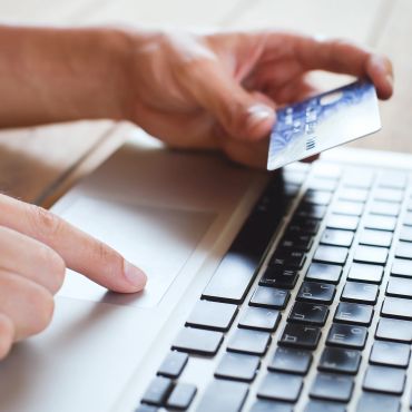 Hands holding a credit card over a laptop keyboard